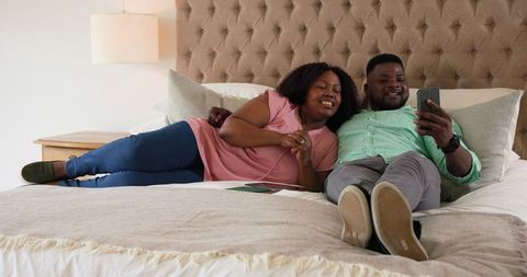 Couple Relaxing in Bed and Sharing Joyful Moments on Smartphone