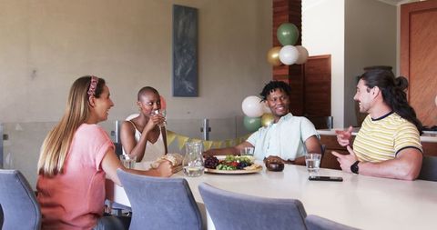 Friends socializing at dining table with food and drinks