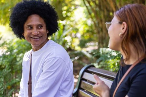 Diverse friends chatting on park bench, smiling and enjoying sunny urban garden conversation