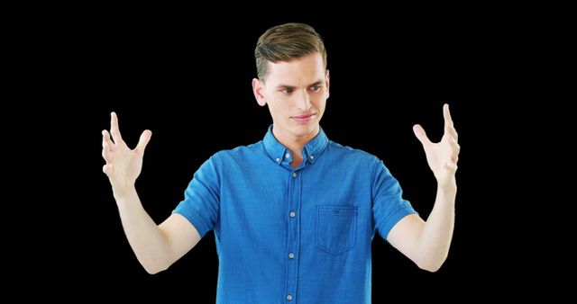 Young man wearing casual blue shirt smiling and gesturing energetically against a black background. Great for use in marketing materials, presentations, or articles related to communication, positivity, or expressive behavior.