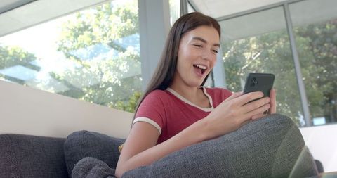 Teenage Girl Smiling at Phone in Cozy Home Environment