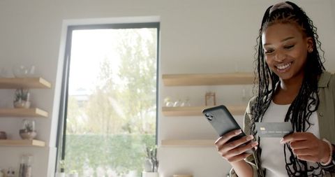 African American Woman Using Phone and Credit Card Next to Kitchen Window - Download Free Stock Images Pikwizard.com