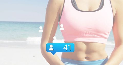 Female fitness influencer showing toned midriff on beach with social media followers badge
