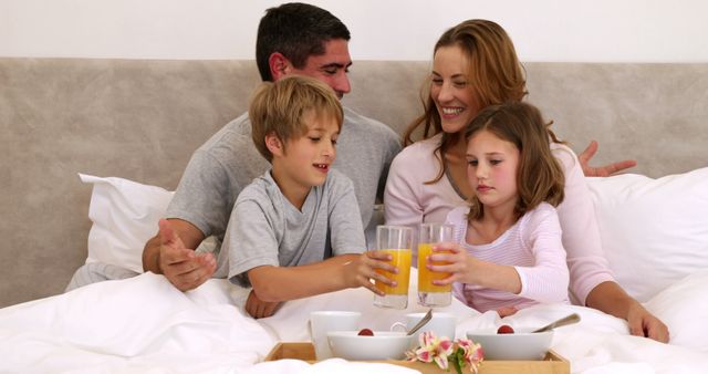 Family enjoying leisurely breakfast in bed together, creating a cozy and warm bonding moment. Ideal for use in articles about family time, healthy breakfasts, weekend activities, or parenting tips.