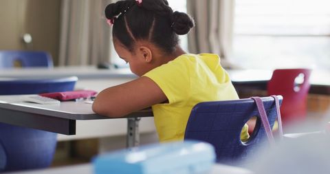 Young schoolgirl studying in classroom enjoying school time