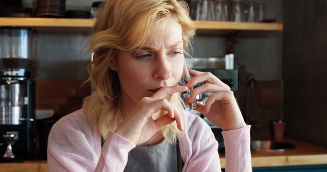 Blonde woman having a serious phone conversation in a cozy cafe - Download Free Stock Images Pikwizard.com