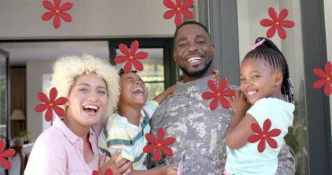 Military dad returning home embracing laughing children at door with red flower decals