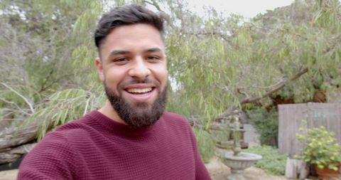 Smiling man posing in tranquil backyard with fountain