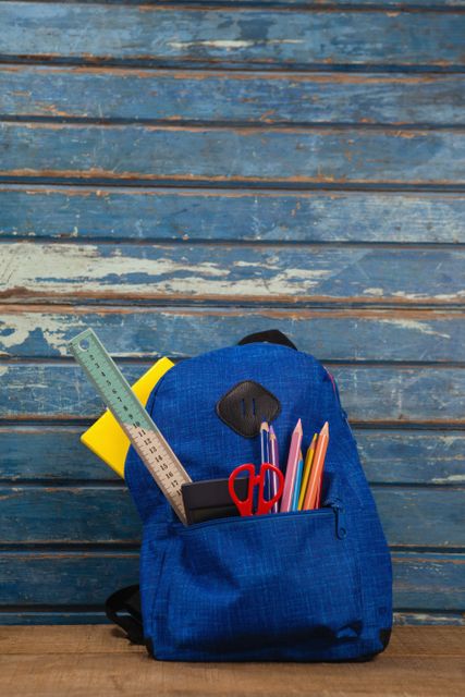 Various supplies in schoolbag on wooden table