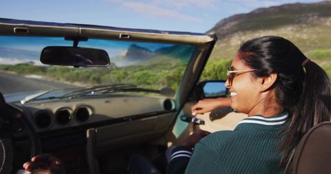 Young Woman Enjoying Scenic Ride in Convertible Near Coastline