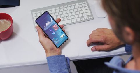 Businessman analyzing financial data on smartphone at workspace