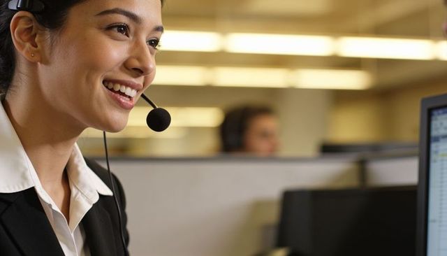Smiling customer service representative wearing headset and blazer in office cubicles
