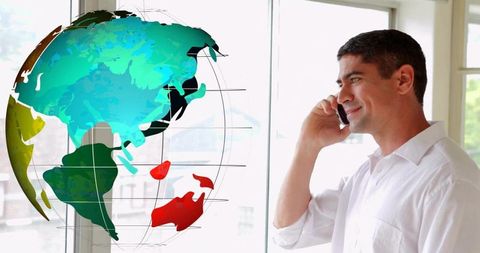 Business executive talking on smartphone by window with colorful world map overlay