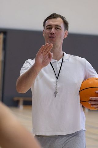 Male Coach Directing Team on Basketball Court