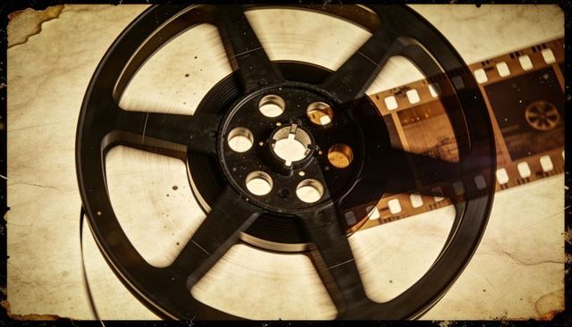Resting vintage film reel on stained parchment with unspooled 35mm strip, sepia grain texture