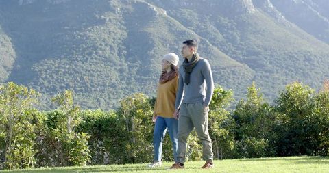 Couple Walking on Scenic Hillside Amidst Mountain Views