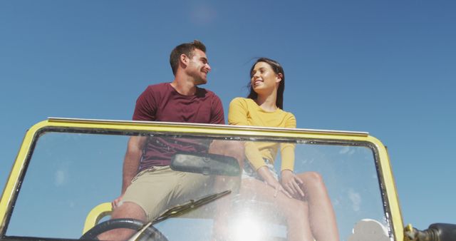 Happy caucasian couple sitting in beach buggy by the sea talking. beach stop off on summer holiday road trip.