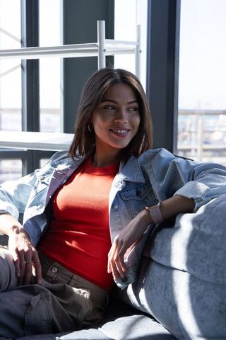 Relaxing young woman lounging in modern harbor lounge wearing denim jacket and smartwatch