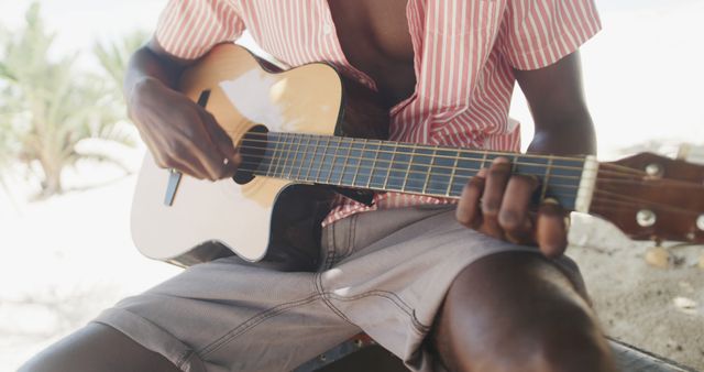 Close-up of person playing acoustic guitar outdoors at tropical beach - Download Free Stock Images Pikwizard.com