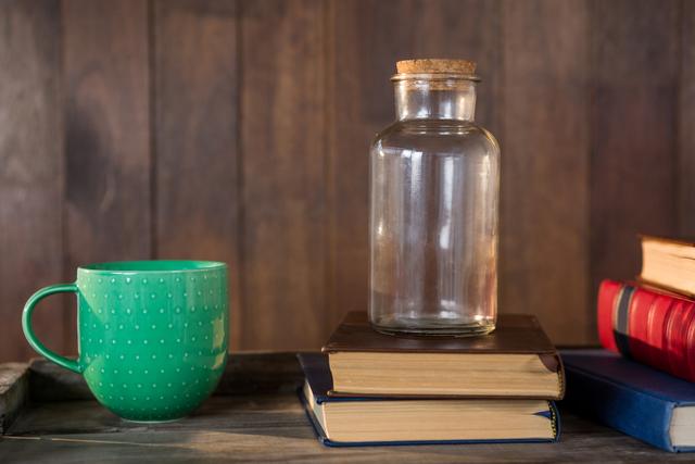Close-up of jar, books and mug on wooden table