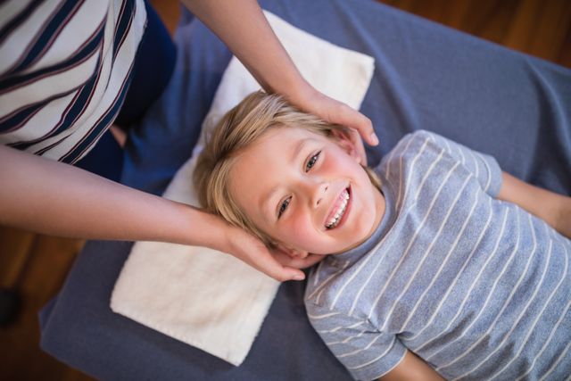 High angle portrait of smiling smiling boy receiving massage from female physiotherapist - Download Free Stock Photos Pikwizard.com