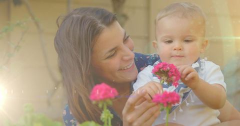 Joyful Mother with Toddler Holding Pink Flowers in Garden Setting