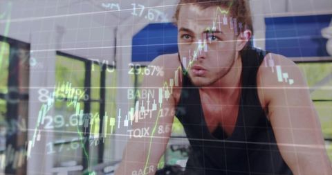 Leaning focused fit man pedaling on stationary bike sweating with charts and data overlaying