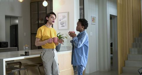Young diverse friends chatting over coffee at modern kitchen island relaxed casual urban apartment