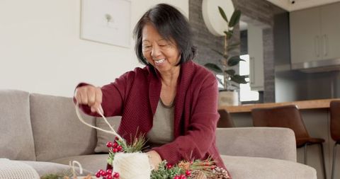 Senior Woman Crafting Festive Décor with Pine Cones and Twine