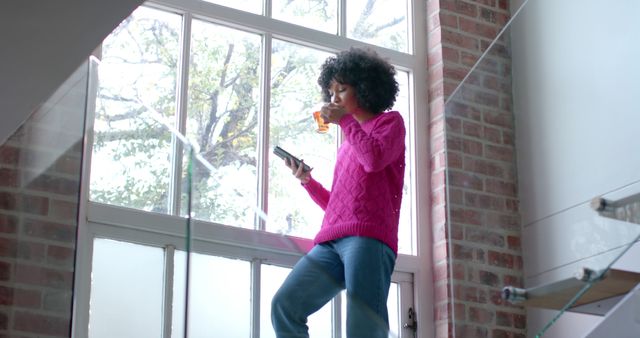 Woman Drinking Juice and Using Phone Near Sunlit Brick Wall - Download Free Stock Images Pikwizard.com