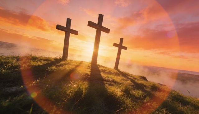 Three wooden crosses on misty hill at sunrise casting golden light and lens flare