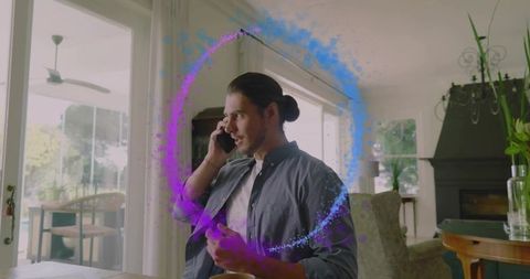 Man talking on phone surrounded by purple augmented reality ring in sunlit home office
