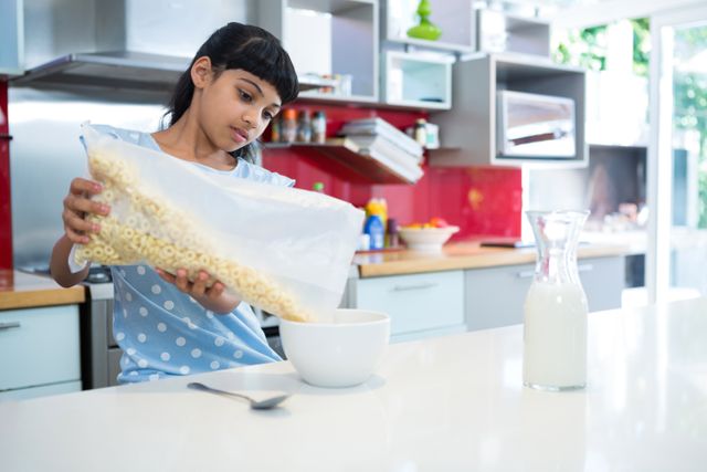 Girl pouring breakfast cereal in bowl on kitchen counter