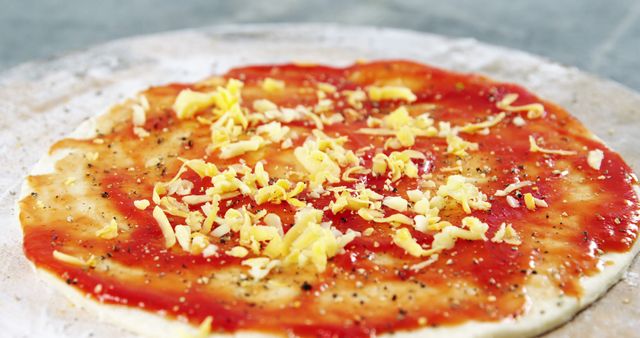 The image depicts the early steps of homemade pizza-making with sauce and cheese applied. - Download Free Stock Photos Pikwizard.com
