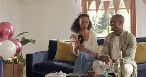 Diverse Couple Celebrating with Smile and Gifts in Cozy Home