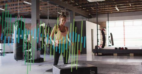 Woman performing plyometric box jumps in industrial gym with fitness analytics overlay