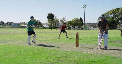 Teen cricket match showing batter defending wicket and wicket-keeper diving to catch ball