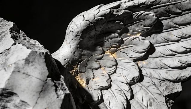 Weathered marble angel wing revealing gold-filled cracks and layered feather texture