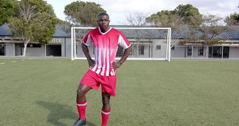 Confident Soccer Player in Red Jersey Stands on Training Field