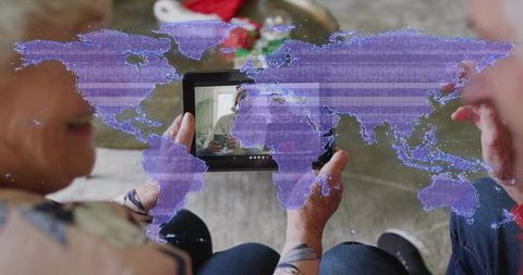 Senior couple video calling on tablet with global map overlay, virtual family connection