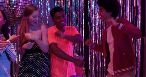 Multiracial friends dancing under disco ball at retro tinsel party