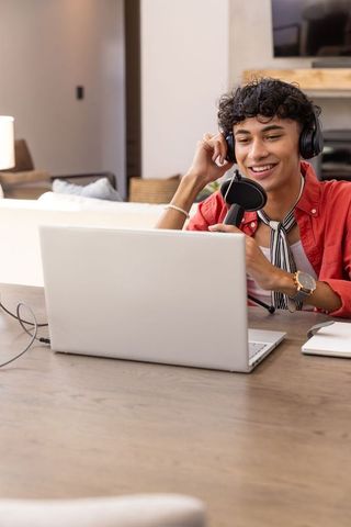 Smiling Podcaster Engaging Audience in Home Recording Studio