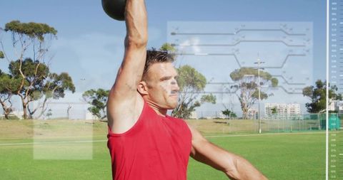 Male athlete lifting kettlebell overhead on sports field with digital hud fitness overlay
