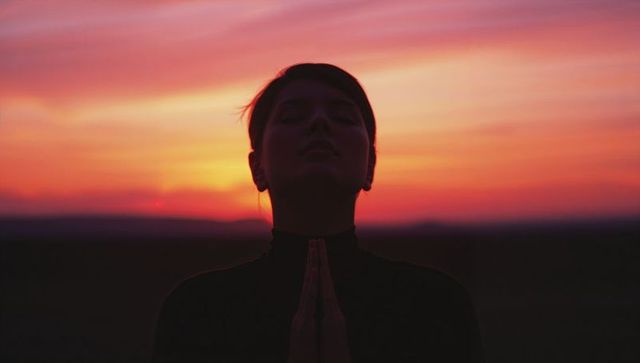 Silhouette of Woman Meditating Amidst Vibrant Sunset Colors