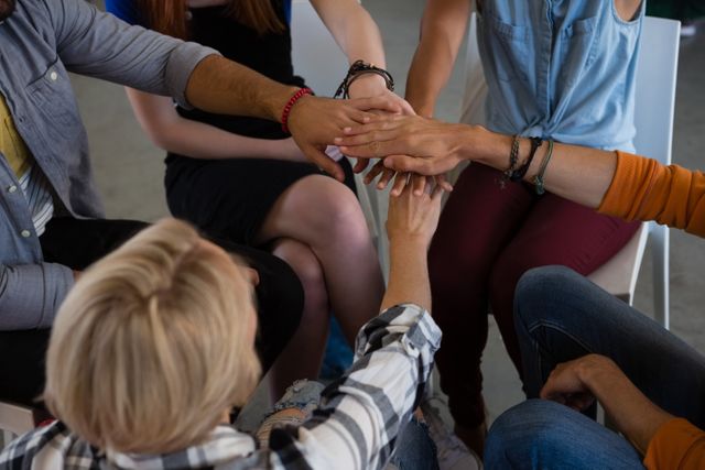 This image shows a group of friends stacking their hands together, symbolizing unity and support. It is ideal for illustrating concepts of teamwork, collaboration, and community. Suitable for use in articles, blogs, and promotional materials related to group activities, support groups, and team-building exercises.