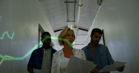 Walking team reviewing reports with green data graph overlay in modern office corridor