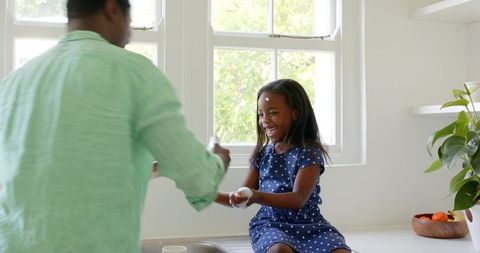 Father and daughter sharing joyful moment washing hands