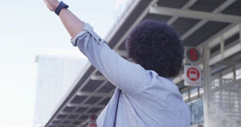 Woman Hailing Taxi in Urban Environment with Raised Hand Gesture