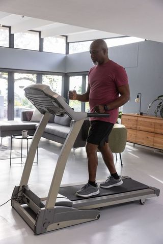 Older Man Exercising on Treadmill in Modern Living Room