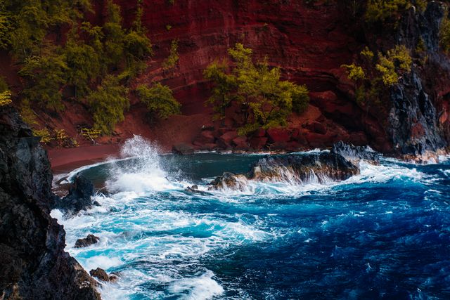 Coastal scene with a dramatic cliff and crashing waves, perfect for travel blogs, adventure magazines, and nature websites. Red sand and lush greenery enhance the exotic and dramatic appeal, highlighting the beauty of untamed seashores. Useful for promotions about travel destinations, posters, and background images for presentations.